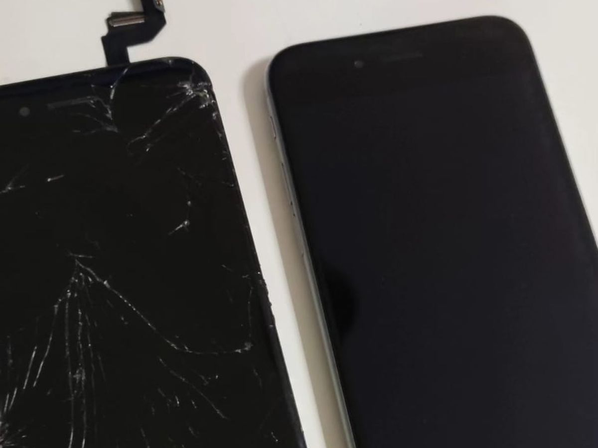 Ecrã de iPhone estalado ao lado do telemóvel com o ecrã novo montado